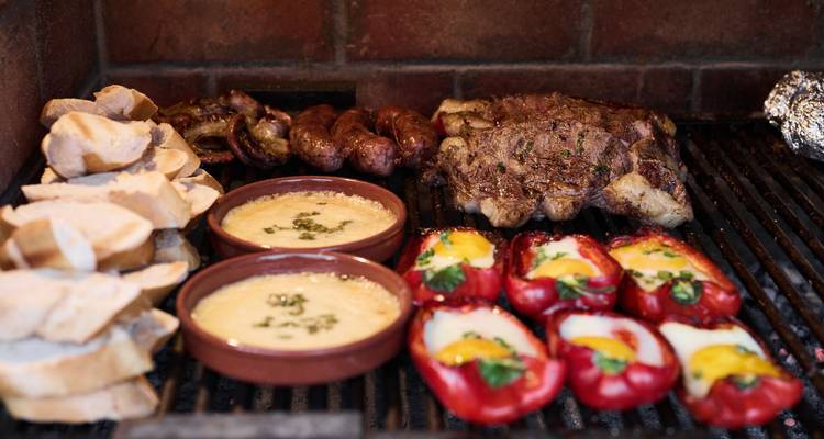 La clásica parrilla argentina cargada de carne, chorizos, pimientos y platos con queso.
