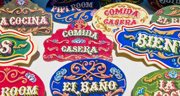 Coloridos carteles pintados a mano al estilo de Buenos Aires con frases en español en una pared del mercado.