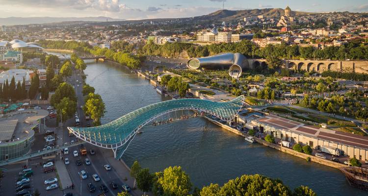 Puente de la Paz cruzando el río Kura en Tiflis con la moderna sala de conciertos y el horizonte de la ciudad más allá.