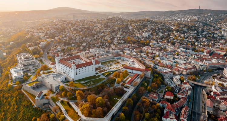 Dramatisch luchtfoto van Bratislava Castle met uitzicht over de stadsgezicht in zacht zonsondergangslicht.
