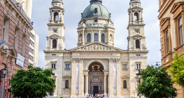 Grand façade of St. Stephen’s Basilica in Budapest framed by leafy trees and bustling visitors.