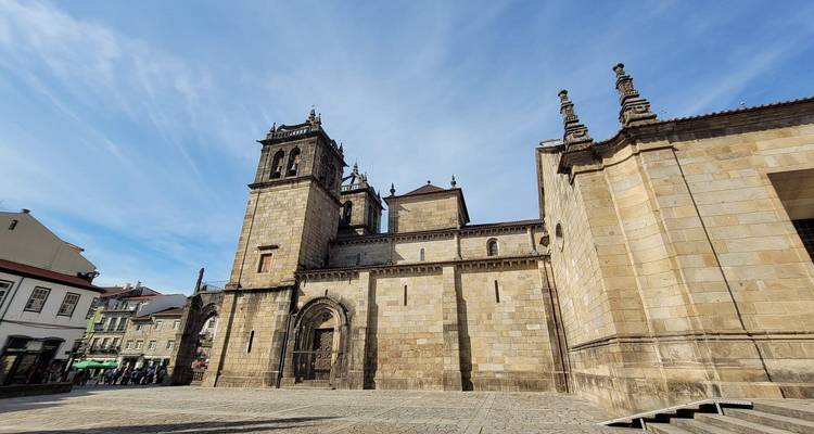 Cathédrale historique en pierre avec deux tours jumelles sous un ciel bleu éclatant dans une place ouverte.