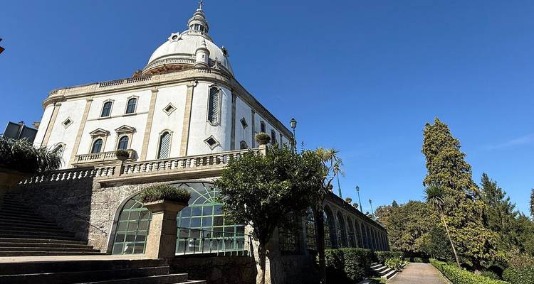 Église aux dômes blancs se détachant sur un ciel bleu profond avec des jardins aménagés.