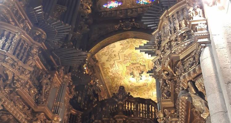 Intérieur d'église richement doré avec tuyaux d'orgue ornementés et boiseries sculptées.