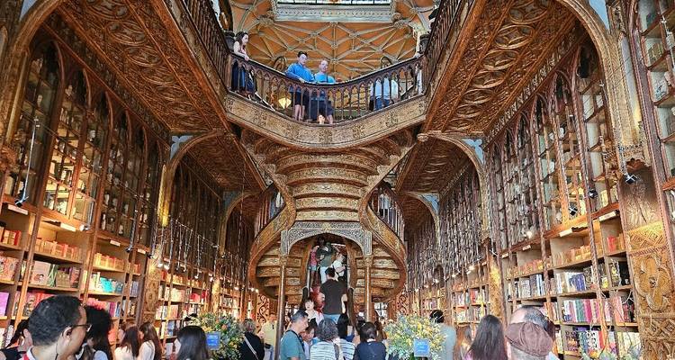 Grande librairie historique avec un escalier en bois ouvragé et des rayonnages remplis de livres.