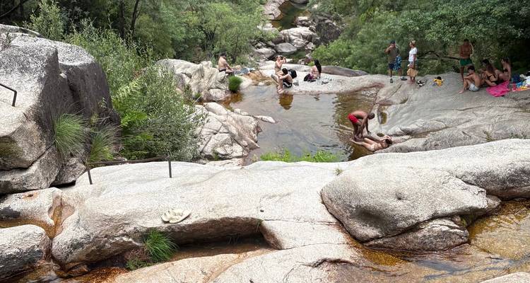 Des bassins naturels de rochers dans un canyon fluvial où les gens se détendent et bronzent sur des dalles de granit.