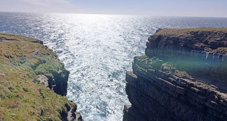 Vue contrejour de la lumière du soleil scintillant sur l'Atlantique entre de hautes falaises.