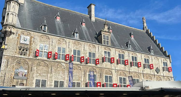 Historic stone town hall with rows of red shutters under a bright blue sky