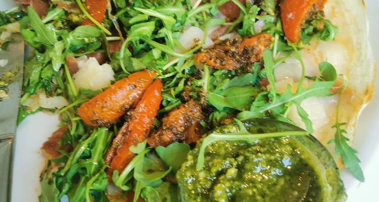 Plate of arugula salad with roasted carrots, prosciutto and pesto