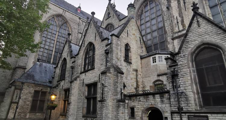 Gothic stone church complex with large arched windows lit by a warm street lamp