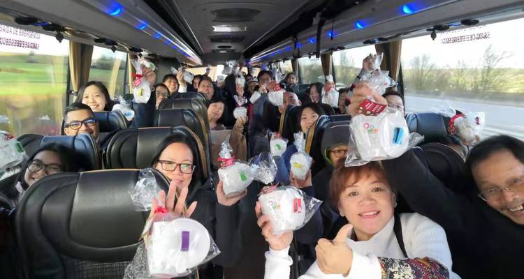 Fröhliche Fahrgäste in einem Reisebus halten Geschenktüten in die Höhe, während sie während der Fahrt sitzen.