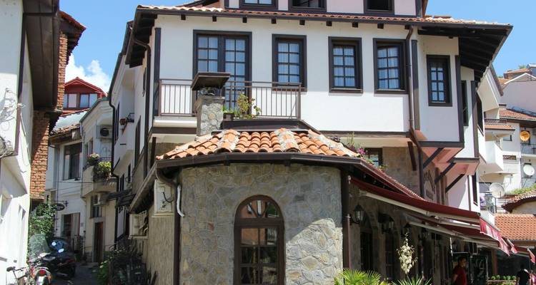 Charmante maison d'époque ottomane aux murs blancs et charpente en bois sombre dans un quartier pavé de galets.