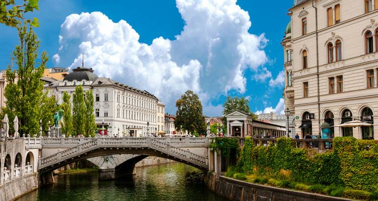 Le Triple Pont de Ljubljana enjambant la rivière Ljubljanica d'un vert émeraude, avec ses bâtiments ornés et ses ciels bleus.