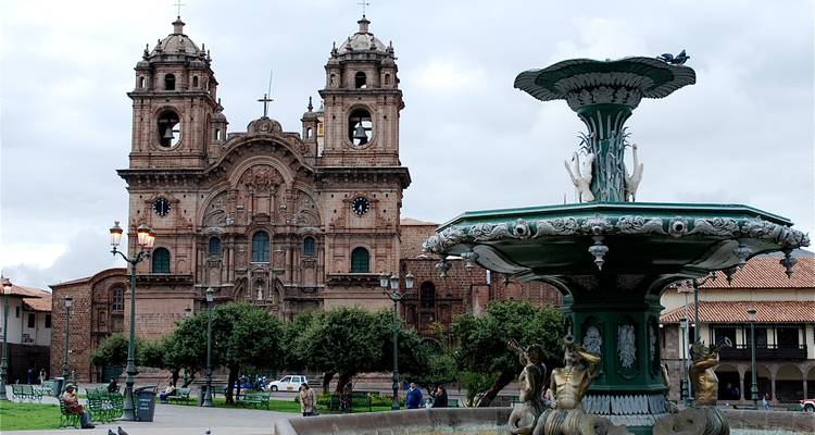 Barockkirchenfassade von Cusco und verzierter Brunnen an einem bewölkten Nachmittag