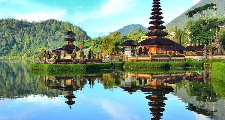 Les eaux immobiles comme un miroir reflétant les pagodes en étages du temple Ulun Danu Beratan contre des montagnes verdoyantes.