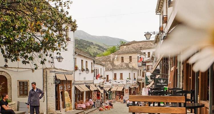 Calle tranquila empedrada en un pueblo de montaña llena de tiendas, con gente local charlando en primer plano