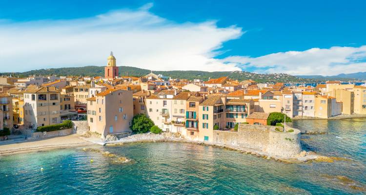 Vue aérienne de la vieille ville de Saint-Tropez avec ses maisons aux couleurs pastel et un clocher prominent surplombant les eaux claires de la Méditerranée.