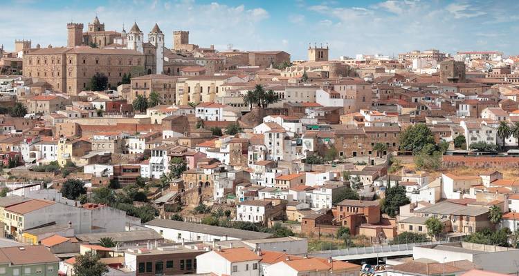 Expansive view over the terracotta roofs and historic towers of Cáceres under a blue sky