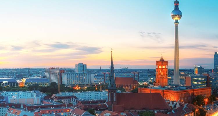 Skyline de Berlin au crépuscule avec la Tour de la télévision et l'hôtel de ville rouge se dressant au-dessus des toits de la ville.