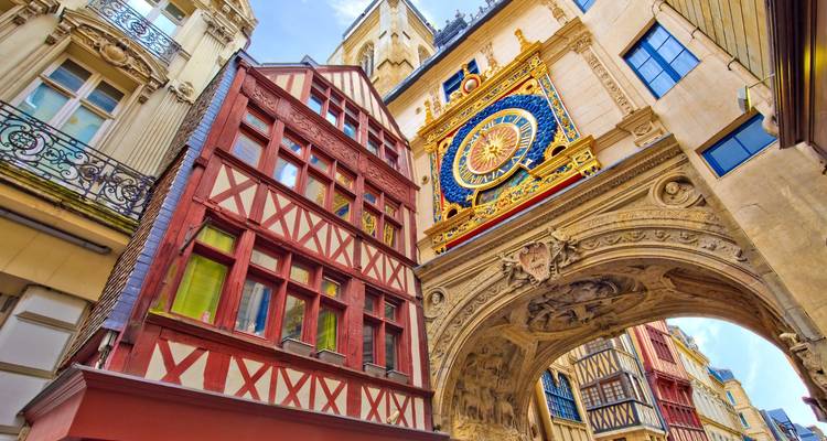 Vue ascendante de l'ornée Gros-Horloge de Rouen entourée de bâtiments médiévaux à colombages.