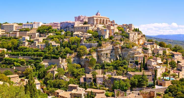 Hilltop-Dorf Gordes in der Provence, das über terrassenförmig angeordneten Steinhäusern und grünen Tälern thront