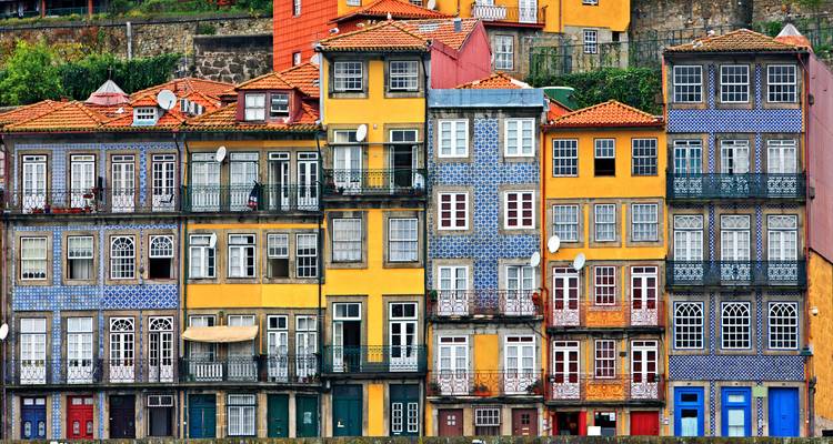 Reihe farbenfroher gekachelter Fassaden mit Balkonen und roten Dächern im Flussufer-Viertel von Porto
