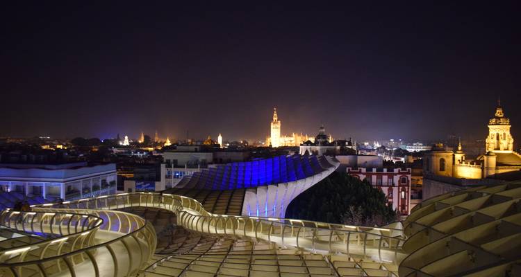 Panorama nocturne de Séville avec le Metropol Parasol illuminé s'étendant sur le premier plan et les flèches de la cathédrale brillant au loin