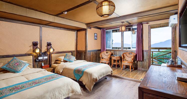 Gemütliches Gästezimmer mit Doppelbetten aus Holz, Terrasse mit Bergblick und Korbstühlen.