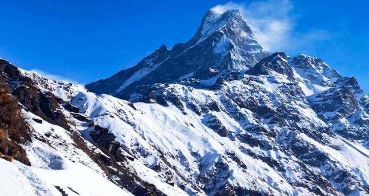 Le pic enneigé de Machapuchare sous un ciel bleu profond avec un léger panache de nuage