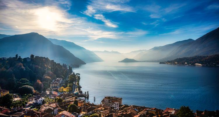 Umfassende Luftaufnahme über dem Comer See mit nebligen Bergen und Sonnenstrahlen