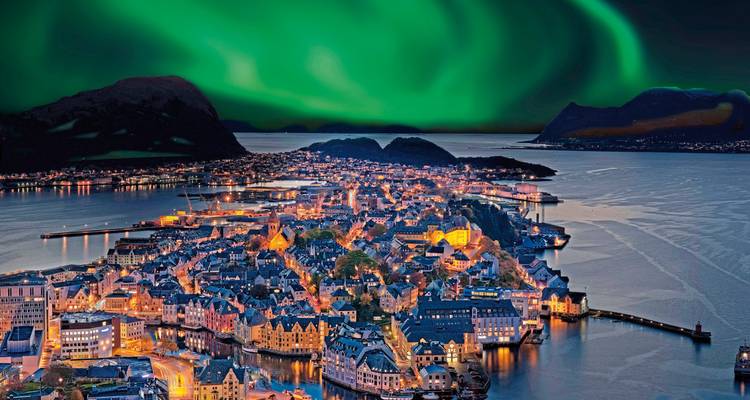 Die Halbinsel Alesund nachts beleuchtet unter einer lebendigen grünen Aurora, die über den Himmel tanzt.