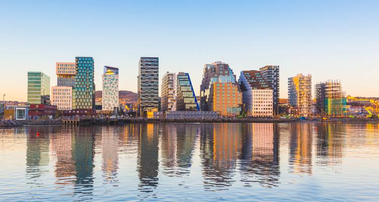 Reflexion der Wolkenkratzer des modernen Barcode-Viertels von Oslo bei Sonnenaufgang auf dem ruhigen Hafenwasser.