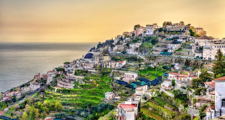 Les terrasses en pente et les villages aux couleurs pastel de la Côte Amalfitaine illuminés par la douce lumière du coucher de soleil.