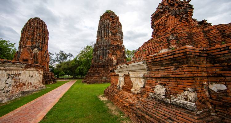 Oude bakstenen tempels en verwoeste muren van het Ayutthaya Historical Park onder een bewolkte lucht