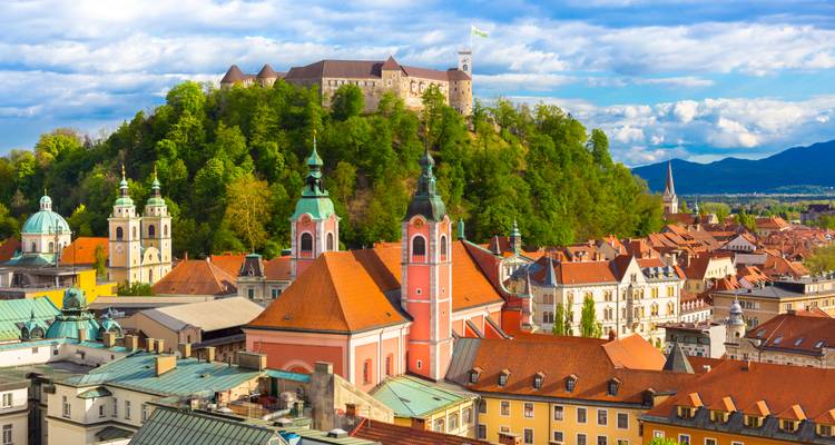 Vue aérienne lumineuse des églises pastel de Ljubljana et de la colline couronnée par un château sous un ciel bleu