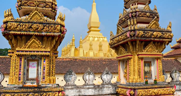 Gouden boeddhistisch stoepa omringd door sierlijke vergulde tempeltorens tegen een blauwe lucht