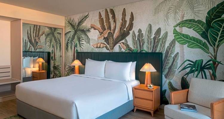 Stilvolles Hotelzimmer mit botanalem Wandgemälde und warmen Holzmöbeln.