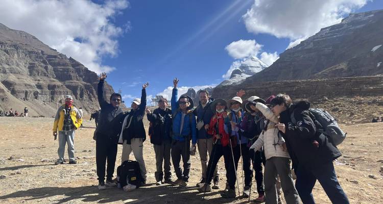 Le groupe de trekking pose avec enthousiasme dans une vallée accidentée en haute altitude avec le Mont Kailash qui se dresse majestueusement à l'arrière-plan.