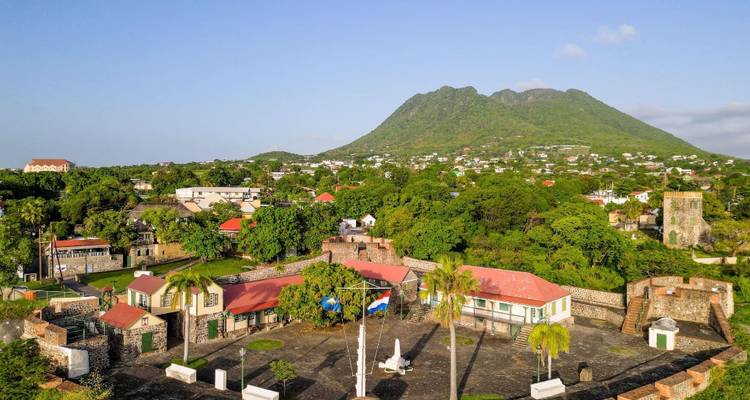 Pueblo histórico del Caribe con edificios de techos rojos rodeados de dos picos verdes gemelos