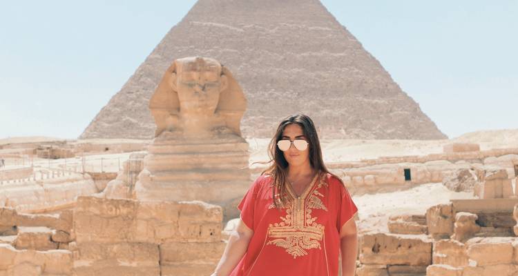 Weibliche Reisende in rotem Kleid posiert vor der Sphinx und der Pyramide des Chephren.