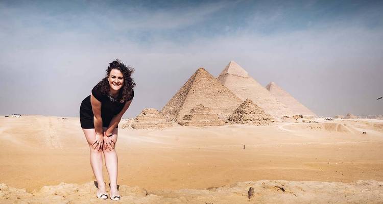 Besucher, der auf einem Aussichtspunkt lächelt und auf die drei Pyramiden von Giza im diesigen Licht blickt.