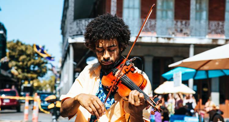 Musicien de rue jouant du violon dans un cadre urbain dynamique avec des passants flous en arrière-plan