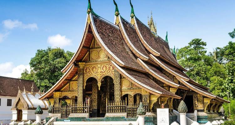 Le temple magnifiquement orné de Wat Xieng Thong avec son toit étagé aux courbes gracieuses se détachant sur un ciel bleu