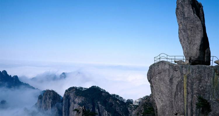 Pilier de granit escarpé et solitaire avec rampe dominant une couverture de nuages dans les pics de Huangshan.