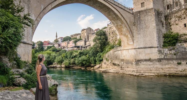 Femme admirant la rivière Neretva turquoise sous le pont en pierre emblématique du Stari Most à Mostar.
