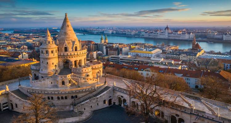 La lumière dorée de l'aube frappe la Citadelle du Pêcheur à Budapest avec des vues panoramiques du Parlement sur le Danube.