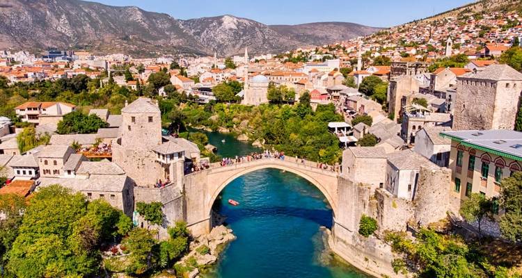 Vue aérienne élevée de l'historique pont-arche Stari Most avec la rivière turquoise et la ville de Mostar.