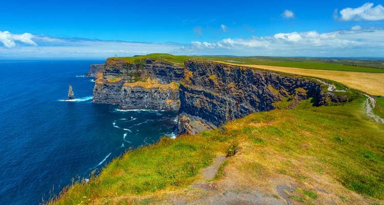 Des falaises maritimes spectaculaires plongeant dans l'océan Atlantique sous un ciel bleu éclatant.