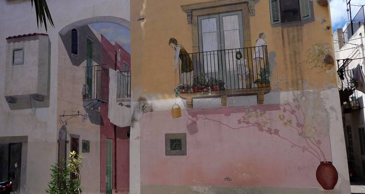 Wall mural depicting village life on a pastel-colored building façade