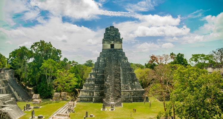 La icónica pirámide del Templo IV se alza por encima de las ruinas de la selva exuberante en Tikal en un día radiante.